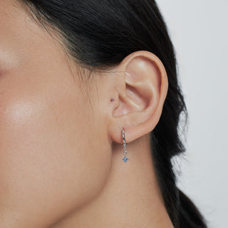 Model wearing a solid charm paired with the hydrangea charm in blue sapphire and white gold